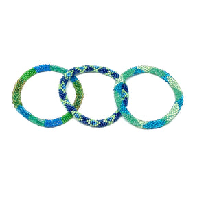 These "Tropical Tide Roll Ons" come as a set of three.  They are handmade with love by women artisans in Nepal, using high quality glass beads and hand-dyed cotton thread. These bracelets will expand over your hand to fit most wrist.   The purchase of these bracelets empowers female artisans through fair trade. Your purchase provides women with fair income + benefits in a safe and healthy work environment. Aid Through Trade empowers women by creating opportunity through beautifully designed jewelry.