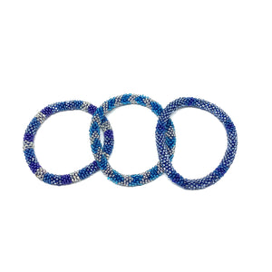 These "Blue Oasis Roll Ons" come as a set of three.  They are handmade with love by women artisans in Nepal, using high quality glass beads and hand-dyed cotton thread. These bracelets will expand over your hand to fit most wrist.   The purchase of these bracelets empowers female artisans through fair trade. Your purchase provides women with fair income + benefits in a safe and healthy work environment. Aid Through Trade empowers women by creating opportunity through beautifully designed jewelry.