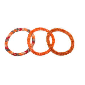 These "Orange Marmalade Roll Ons" come as a set of three.  They are handmade with love by women artisans in Nepal, using high quality glass beads and hand-dyed cotton thread. These bracelets will expand over your hand to fit most wrist.   The purchase of these bracelets empowers female artisans through fair trade. Your purchase provides women with fair income + benefits in a safe and healthy work environment. Aid Through Trade empowers women by creating opportunity through beautifully designed jewelry.