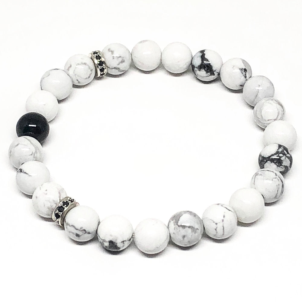 This white howlite and black agate natural stone bracelet is perfect to add to your collection.  If you love black and white you will love this bracelet! Howlite is predominantly a calming stone. It is used when needing to reduce anxiety, tensions and stress. It can also be used to facilitate awareness, encourage emotional expression and assist in the elimination of pain, stress and/or rage. Fits size M-L.   8mm White Howlite Beads  Black Cubic Zirconia   Silver Plated Brass 